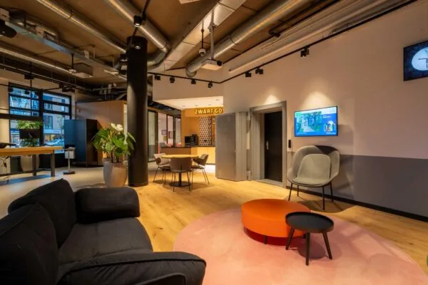 Moderne en gezellig ingerichte wachtruimte met zitmeubilair, planten en de koffiebar Zwart Goud op de achtergrond.